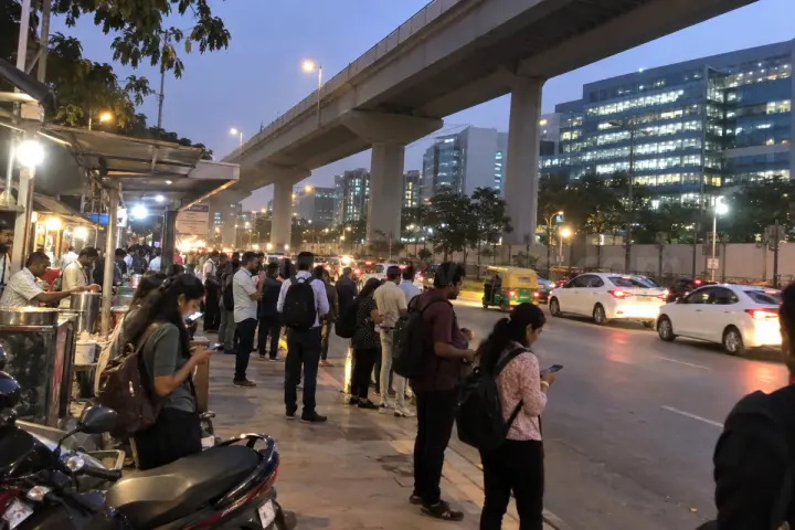 Office crowd at a bus stop under the Electronic City flyover