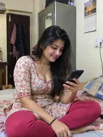 Desi girl in a kurti sitting on her bed with her phone