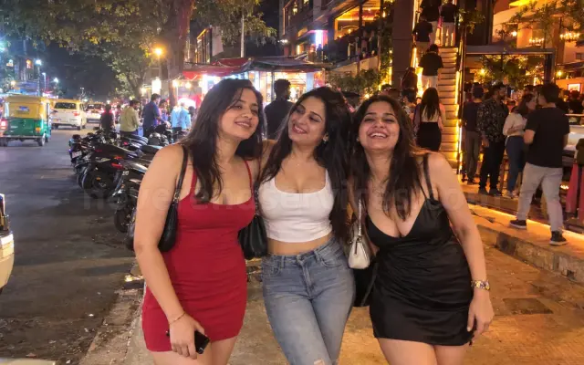 Three girlfriends in party dresses on a Koramangala street at night