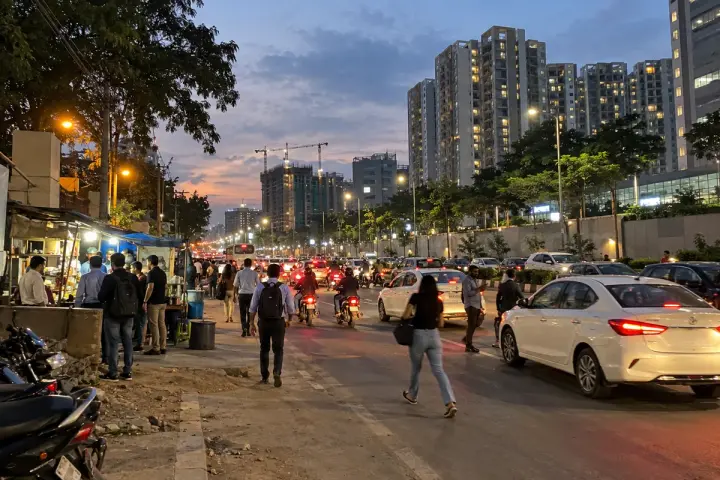 Evening traffic on Sarjapur Road with apartment towers behind