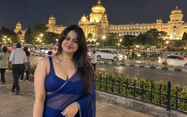 Woman in a blue saree across the road from the lit Vidhana Soudha