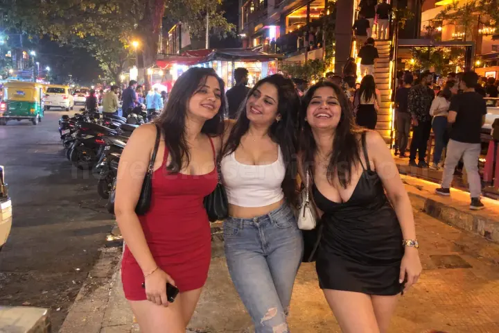 Three girlfriends in party dresses on a Koramangala street at night