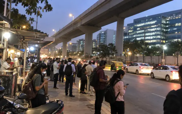 Office crowd at a bus stop under the Electronic City flyover