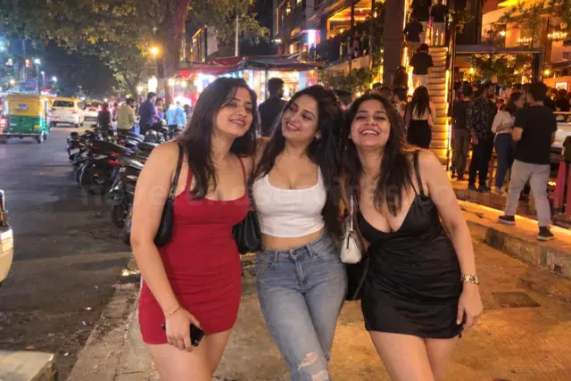 Three girlfriends in party dresses on a Koramangala street at night