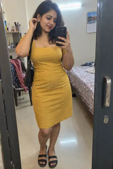 Bangalore escort getting ready at home, a mirror selfie in a mustard-yellow dress