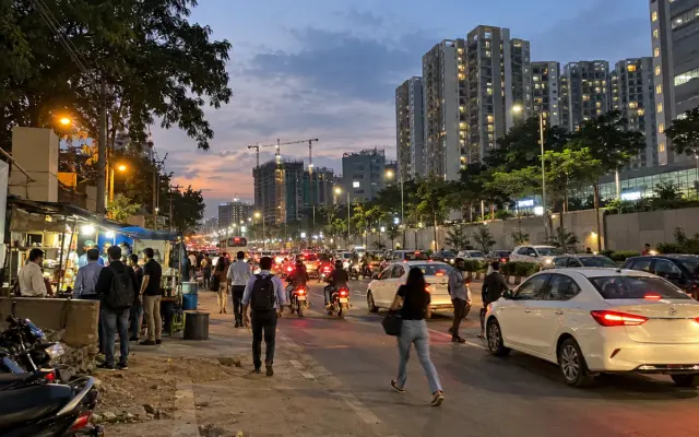 Evening traffic on Sarjapur Road with apartment towers behind